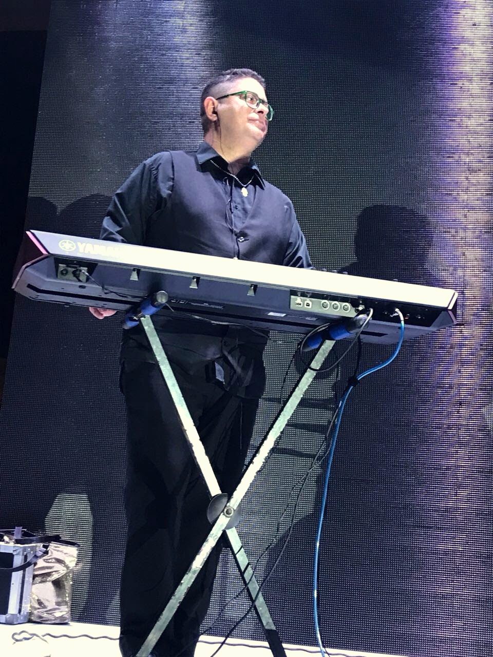 Yan Kayary solo al teclado en un escenario con luces azules