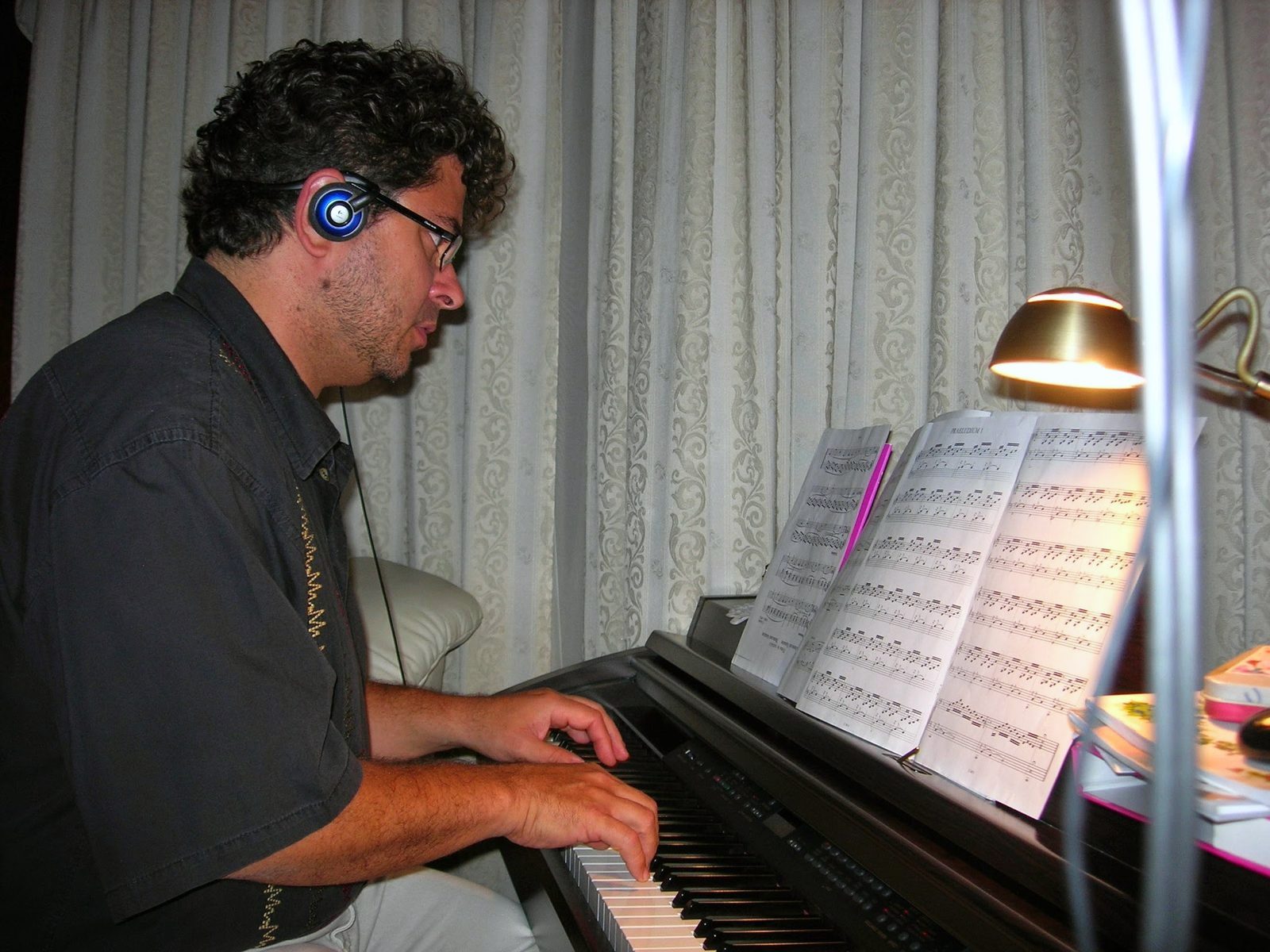 Yan Kayary con auriculares, leyendo una partitura al piano