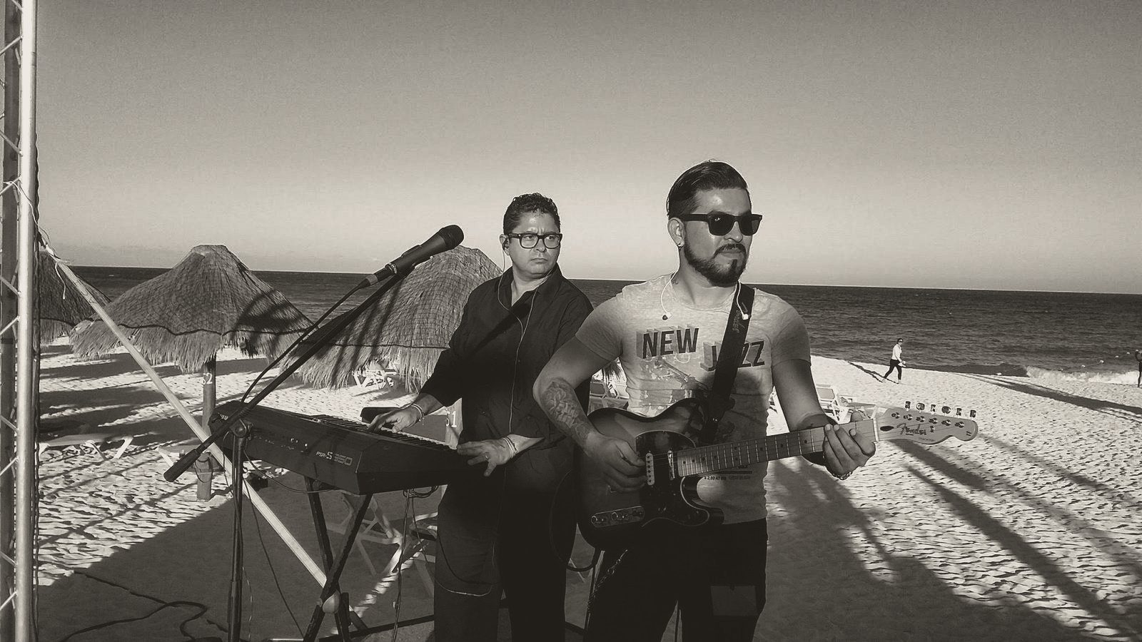 Yan al teclado junto a un guitarrista, frente al mar